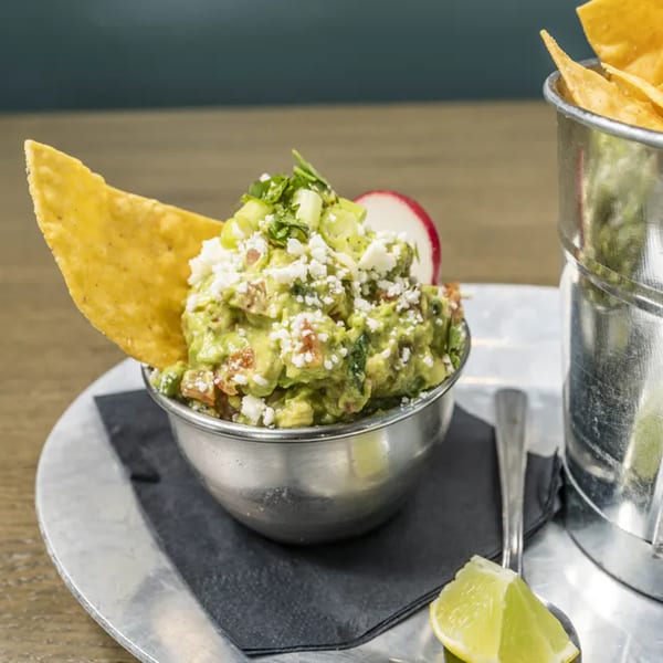 Vida Taco Bar's guacamole with cotija cheese, scallions, and a tortilla chip, served with lime.